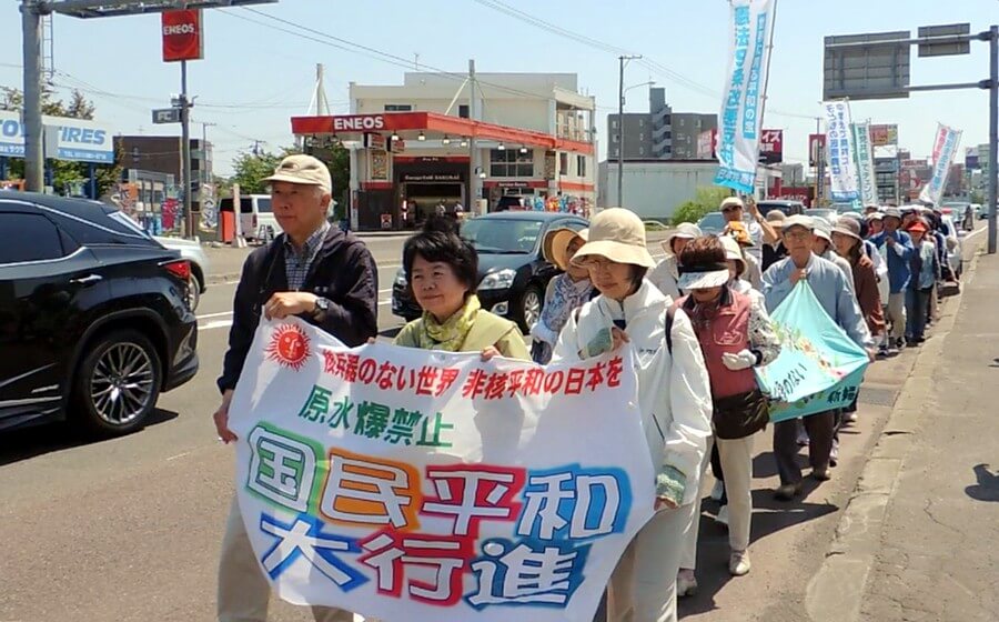 日本共産党の吉岡弘子市議（前列中央）らを先頭に行進する「国民平和大行進清田区コース」の参加者