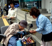 電動車椅子で署名する高齢の買い物客