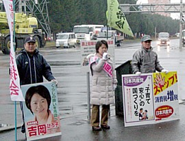 小雨の中、通勤客らに呼びかける吉岡さんと後援会員