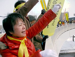 参加者とともに歩道橋上から消費税増税反対をアピールする吉岡さん＝13日
