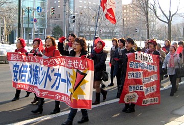 集会後赤い帽子やマフラーなどを身に着けてパレードする女性たち