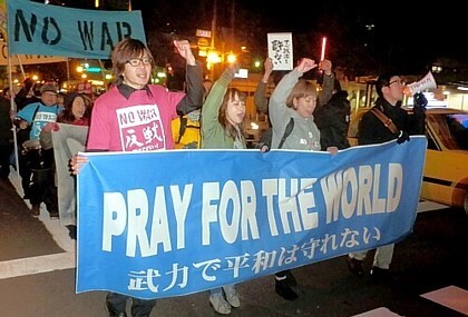 PRAY FOR THE WORLD（世界のために祈ろう）の横断幕を先頭に行進する人たち