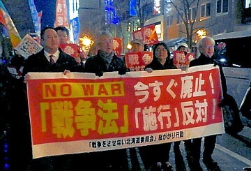 戦争法の施行反対を訴えてデモ行進する人たち
