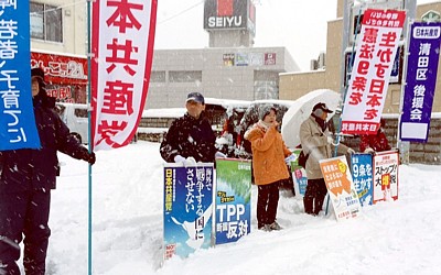 激しい雪のなか、街頭で宣伝する吉岡さんと後援会員