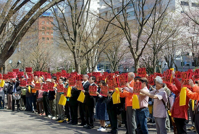 桜が満開の大通公園の広場で「NO！　WAR！」のメッセージを掲げる人たち