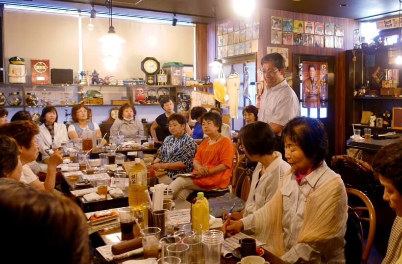 昭和レトロに満ちた店内で、集まった人たちに新しい政治への展望を話す川部さんと吉岡さん（川部さんの前方）ら