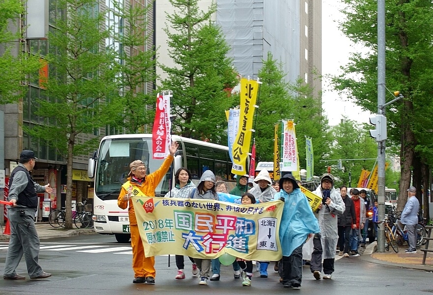 全国通し行進者の山内金久さん（左端）を先頭にビル街を行進する平和行進