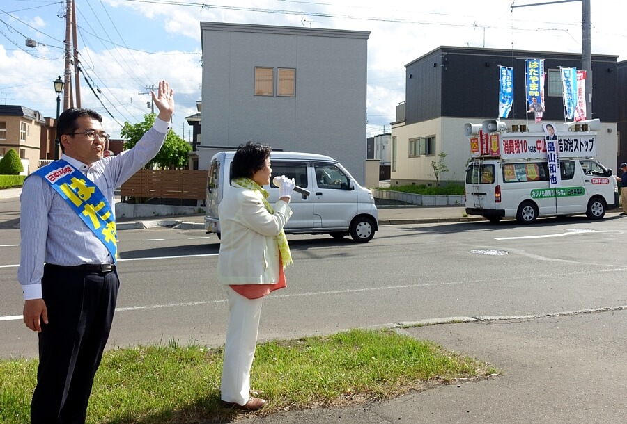 住宅街の食品スーパー前で「札幌キャラバン」の宣伝カーで訴える吉岡市議とはたやま前衆院議員