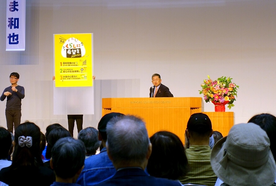 「暮らしに希望を」のパネルを示し、日本共産党の躍進を熱く訴える小池晃書記局長